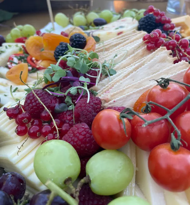 Cheese board detail with grapes, dried apricots, blackberries, red currants and cherry tomatoes on the vine