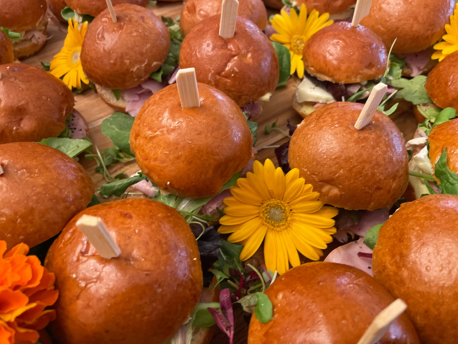 Brioche sliders on skewers arranged with fresh orange and yellow flowers